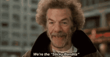 a man with curly hair and a beard is smiling and saying we 're the sticky bandits