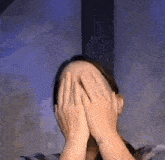 the woman is covering her face with her hands .