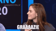 a woman is holding a microphone in front of a blue screen that says graaaazie
