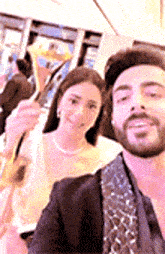 a man and a woman are taking a selfie together . the man is wearing a suit and tie .