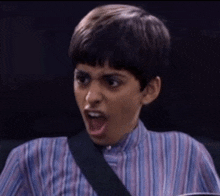a young boy in a striped shirt is making a surprised face