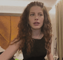 a woman with curly hair is wearing a black tank top and a necklace