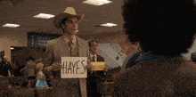 a man holding a sign that says hayes