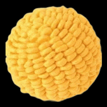 a close up of a yellow ball with a knitted pattern on a black background .