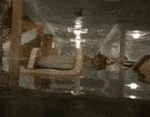 a flooded room with stairs and a chandelier in the background .