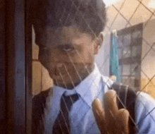 a man in a suit and tie is looking out of a window .