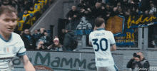 a soccer player with the number 30 on his jersey stands in front of a banner that says mamma