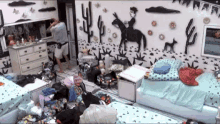 a man standing in a messy room with a cowboy on a horse mural on the wall