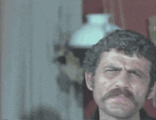 a man with a mustache is making a face in front of a framed picture