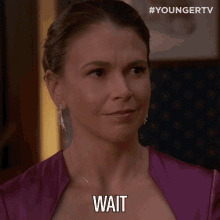 a woman in a purple dress says " wait "