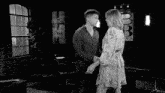 a man and a woman kissing in a black and white photo .