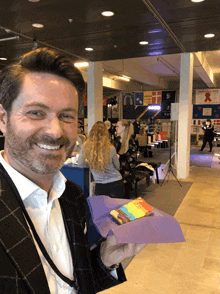 a man holding a rainbow colored candy bar in front of a sign that says danmark