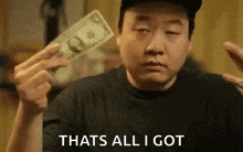 a man is holding a dollar bill in his hand and says `` thats all i got '' .