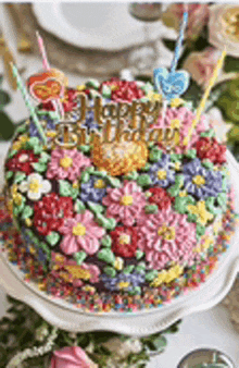 a birthday cake decorated with flowers and sprinkles is on a white plate .