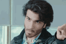 a man with a beard is pointing at the camera and says " get out "
