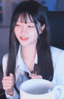 a girl with long hair is sitting next to a cup of coffee .