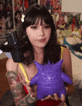 a woman is holding a purple toy in her hands