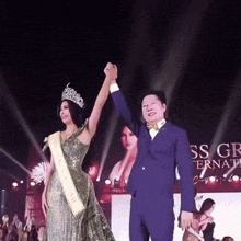 a man and a woman are holding hands in front of a sign that says ' ss gr international '