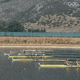 a group of rowers are racing in a lake with the olympic rings in the background