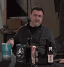 a man is sitting at a table with a bottle of beer and a book called hands of steel