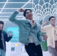 a man in a blue jacket is dancing with other men in a room .