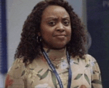 a woman with curly hair wearing a lanyard around her neck is making a funny face .