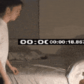 a man is standing in front of a bed with a clock that says 00 : 00