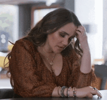 a woman sitting at a table with her hand on her head .