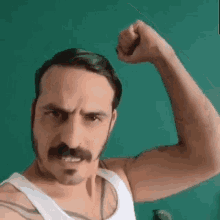 a man with a mustache and white tank top is flexing his arm .