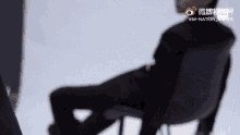 a man in a black suit is sitting in a chair with a white background