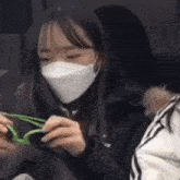 a woman wearing a face mask is holding a pair of sunglasses .