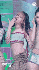 a woman in a crop top and plaid skirt is dancing in front of a sign that says fried chicken