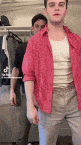 a man wearing a red striped shirt is standing next to another man
