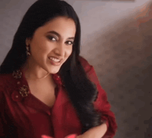 a woman with long black hair is wearing a red shirt and earrings .