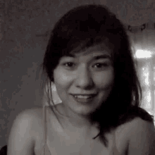 a black and white photo of a smiling woman in a bra