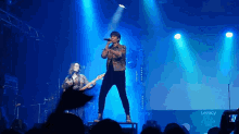 a man singing into a microphone on a stage in front of a legacy logo