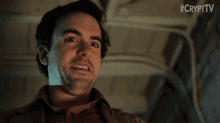 a man with a beard is making a funny face while wearing a brown jacket .
