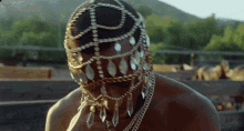 a close up of a man wearing a necklace and a veil