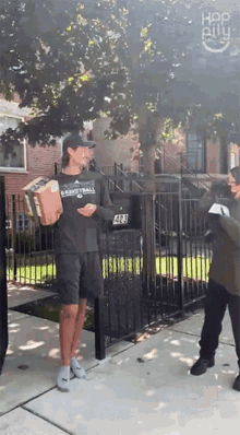 a man standing on a sidewalk holding a box with the number 428 on the mailbox
