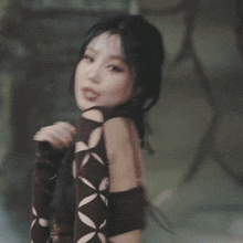 a woman in a brown crop top is dancing in front of a tree .