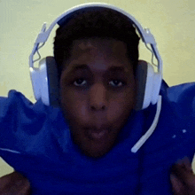 a man wearing headphones and a blue shirt is making a face .