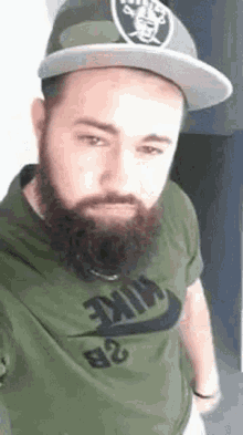 a man with a beard wearing a hat and a nike shirt .
