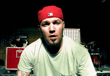 a man wearing a red hat and a green shirt with the letter g on it