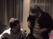 a man wearing a hat is talking to another man in a dark room