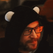 a man wearing glasses and a black hat with white ears is smiling