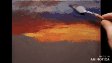 a person is painting a sunset on a canvas