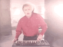 a man in a red shirt is playing an electronic keyboard .