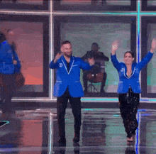 a man and a woman are dancing on a stage with their hands in the air