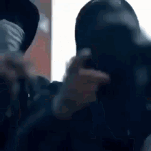 a man wearing a mask is taking a picture of another man 's face .