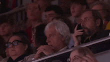 a group of people are sitting in a stadium and one of them has glasses on
